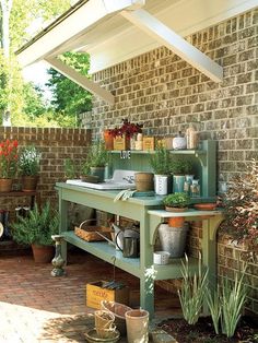 an outdoor kitchen with potted plants and pots on the stove top in front of a brick wall