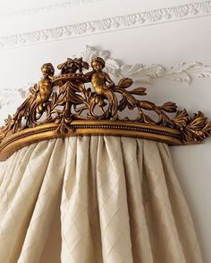 an ornate curtain valance hanging on the side of a white wall with gold trim