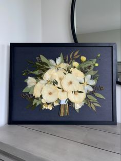 a bouquet of flowers sitting on top of a wooden table in front of a mirror