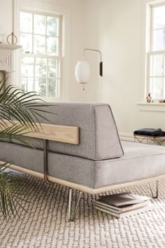 a grey couch sitting on top of a rug next to a window