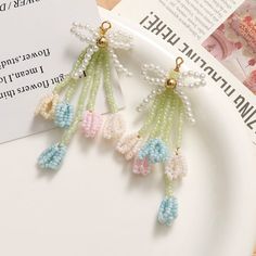 three pairs of earrings with pearls hanging from them on top of a plate next to a book