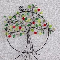 a wire tree with red and green leaves hanging from it's sides on a white wall