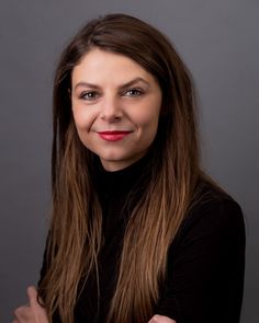 a woman with long brown hair smiling at the camera while wearing a black turtle neck sweater