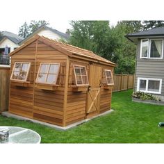 a small wooden shed sitting in the middle of a yard