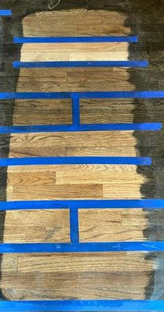 wood flooring being painted with blue tape