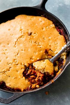 a skillet filled with baked food on top of a counter next to a spatula