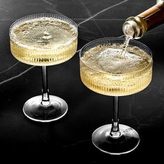 two glasses filled with champagne being poured into them