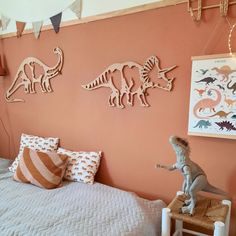 a bedroom decorated in pink and orange with dinosaurs on the wall