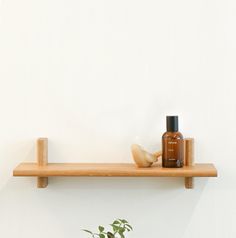 a wooden shelf with bottles on it and a potted plant in the corner next to it