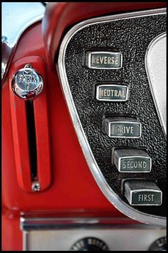 the control panel on an old car is black and red with silver lettering that says reverse, central, second, first