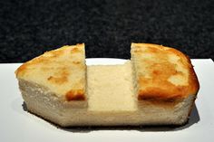 a piece of bread that has been cut in half on a white plate with a black background