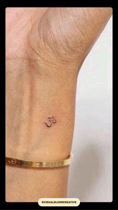 a woman's wrist with a small tattoo on the left side of her arm