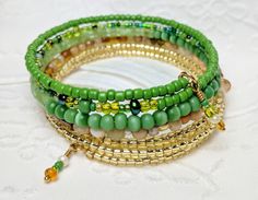 Memory wire bracelet Gold-Lined Glass Beads Sea green, grass green, light green and everything in between glass beads. Green Tiger's beads Varying shades of Tan and Cream glass beads 7/8 - 1 inch in width Naturally and comfortably adjusts to fit any size wrist Dangles add a beautiful detail Fun, Casual, Beautiful unique, eye catching piece Please contact me with any questions and requests. Thank you! Green Beaded Bangle With Spacer Beads, Green Beaded Bangle Bracelets With Spacer Beads, Green Stretch Bangle Bracelet With Colorful Beads, Green Stretch Bangle With Colorful Beads, Green Beaded Bracelets With Czech Glass, Green Beaded Czech Glass Bracelets, Green Czech Glass Beaded Bracelets As Gift, Adjustable Lime Green Beaded Bracelets, Green Hand-strung Beaded Bangle