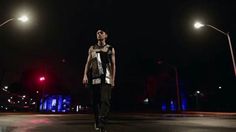 a young man standing on top of a skateboard under street lights at night time