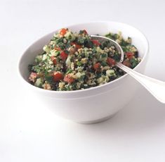 a white bowl filled with vegetables on top of a table next to a spoon and the words la tabule de quinoa