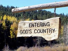 a sign that says entering god's country hanging from the side of a wooden pole