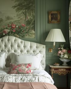 a white bed sitting next to a green wall with flowers on the headboard and pillows