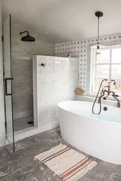 a bath tub sitting next to a window in a bathroom with tile floors and walls