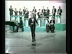 a man in a tuxedo standing on a stage with musical instruments behind him