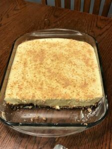 a cake sitting on top of a wooden table next to a glass dish filled with frosting