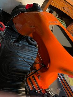 an orange scooter parked in a garage next to a wooden table and chair