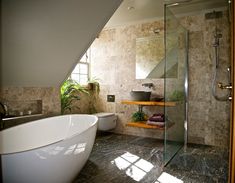 a bathroom with a bathtub, toilet and sink under a slanted ceiling area