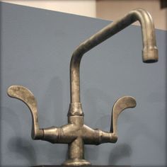 a metal faucet mounted to the side of a wall