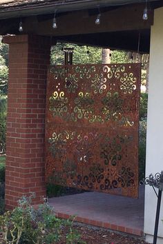 an iron gate in front of a brick building with lights hanging from it's roof