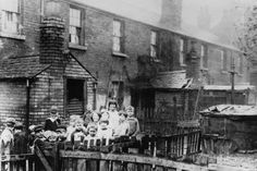 an old black and white photo of children on a bridge in front of a brick building