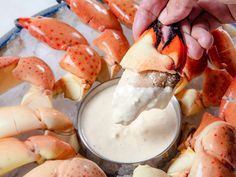 a person dipping some kind of sauce into crab legs