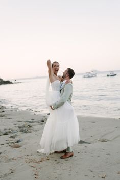 a bride and groom on the beach holding each other