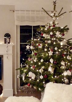 a living room with a christmas tree in the corner and a tv on it's stand