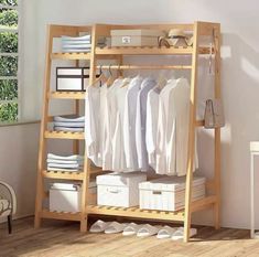 a wooden shelf filled with white shirts and other items next to a chair in front of a window