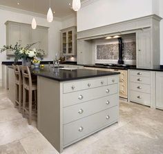 a large kitchen with white cabinets and black counter tops, along with bar stools