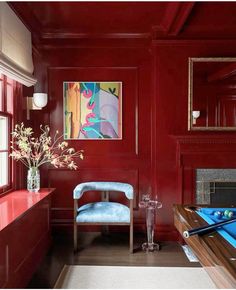 a pool table in a room with red walls and wood trimmings, along with a painting on the wall