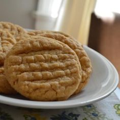 three cookies on a white plate sitting on a table