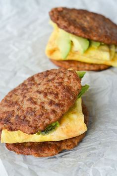 two breakfast sandwiches are sitting on wax paper