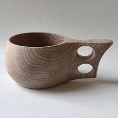 a wooden bowl with holes in it on a white surface, and the bottom half is made out of wood