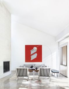 a living room filled with furniture and a red painting on the wall above it's fireplace