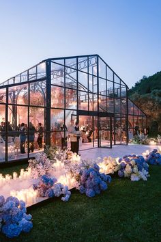 a glass house with flowers and candles on the ground