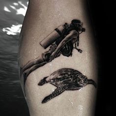 a black and white photo of a person with a sea turtle on his arm, under water