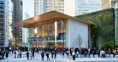 an apple store in the middle of a city with lots of people walking around it