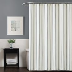 a white shower curtain in a bathroom next to a black table with a potted plant on it