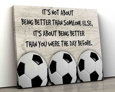 three soccer balls sitting in front of a sign that says it's not about being better than someone else, its about being better than you were the day before