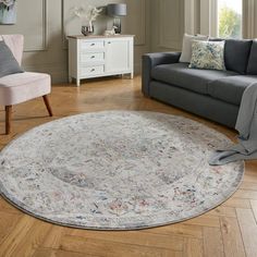 a living room filled with furniture and a rug on top of a hard wood floor