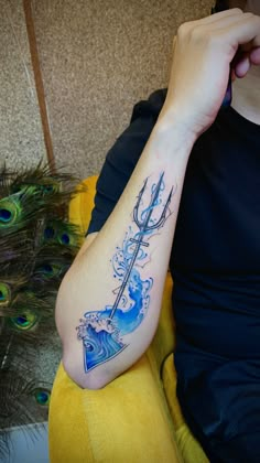 a person with a blue tattoo on their arm holding a peacock tail and an arrow