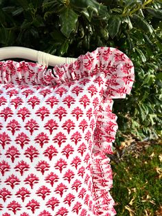 a red and white pillow sitting on top of a green bush