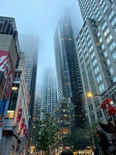 people walking down a street in the city on a foggy day with tall buildings