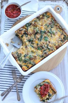 a casserole dish with spinach, cheese and tomato sauce on the side