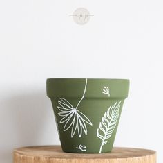 a green planter sitting on top of a wooden table next to a white wall